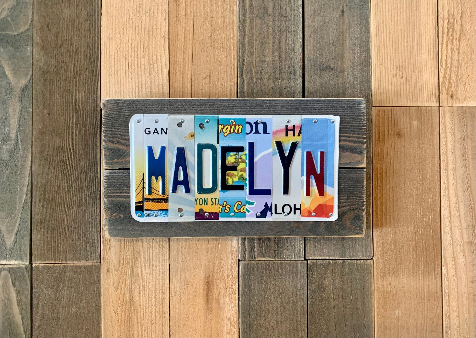 girls name Madelyn spelled out using cut license plate pieces from Michigan license plates, Mississippi license plates, Arizona license plates, USVI license plates, Oregon license plates, Hawaii license plates, Nevada license plates