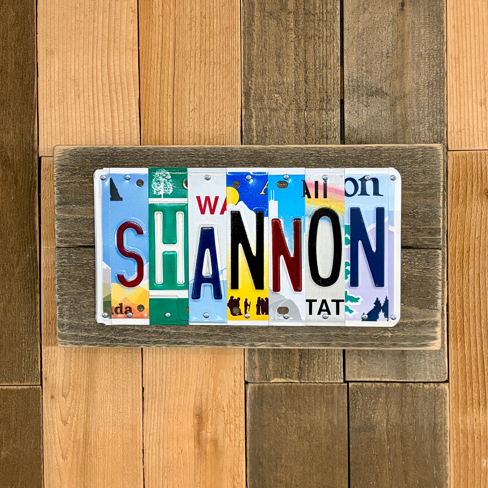 License plate art spelling 'SHANNON' on a wooden background