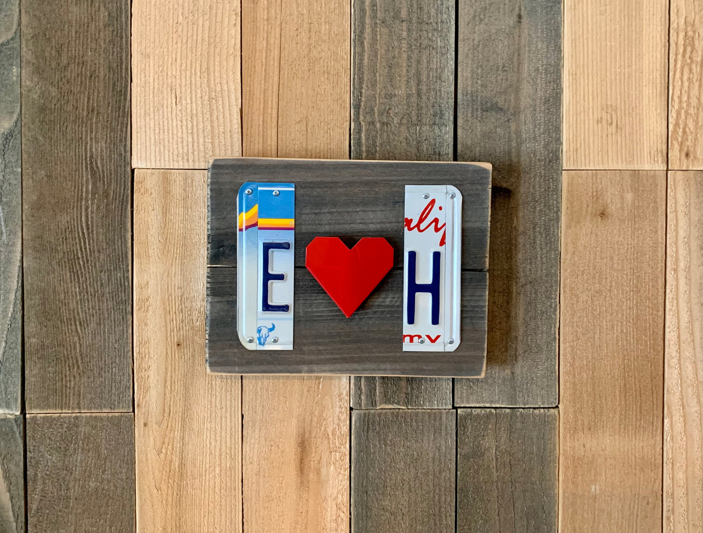 Decorative sign with license plates and a heart on a wooden surface